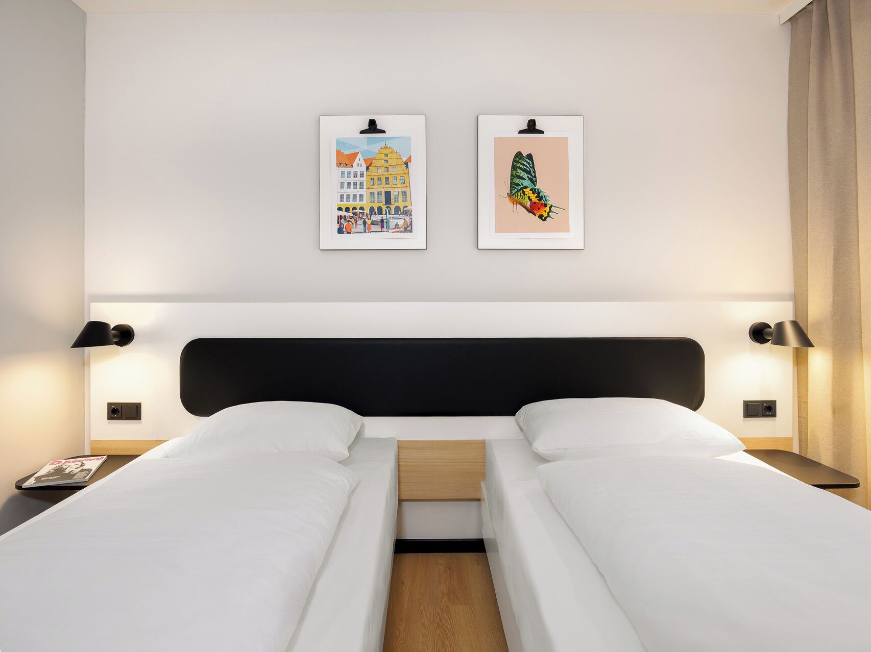 Una habitación de hotel con una cama doble, dos mesitas de noche y dos lámparas de pared.