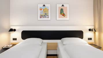 Une chambre d’hôtel avec un lit double, deux tables de chevet, une petite table et deux lampes fixées au mur.