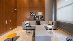 A modern living room with a sectional sofa, a coffee table, and a small side table. There are abstract wall art pieces above the sofa. - Linea Home (São Paulo)