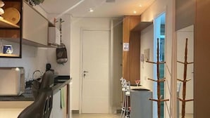 A compact hotel room with a kitchenette, a dining area with a small table and chairs, and a bed. - Linea Home (São Paulo)