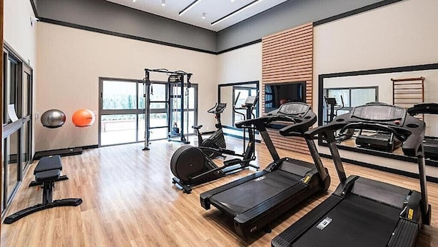 A modern gym with treadmills, exercise bikes, and free weights. - Linea Home (São Paulo)
