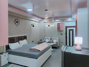 A modern bedroom with a bed, bedside tables, a desk, chairs, and a mirror. - Luxury Studio Apartment at Noida (Noida)