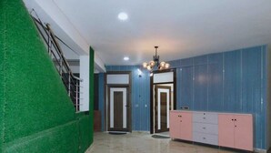 A hallway with a green wall, a staircase, two doors, and a pink and white cabinet. - Luxury Studio Apartment at Noida (Noida)