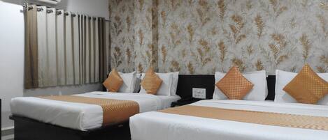 Habitación de hotel con dos camas, un radiador, un equipo de aire acondicionado y un papel tapiz estampado.