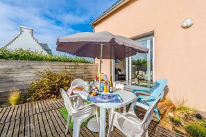 Une terrasse extérieure avec une table, des chaises et un parasol.