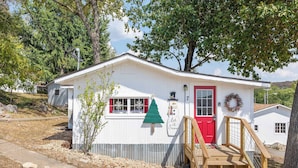 Un pequeño edificio blanco con una puerta roja, una decoración de muñeco de nieve y una escalera de madera que conduce a la entrada.