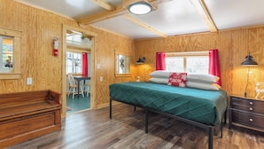 Una habitación con paneles de madera, una cama, un escritorio y un banco.