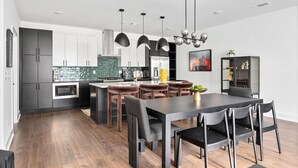 A modern kitchen with dark cabinets, a central island, and pendant lighting. - Rooftop Hot Tub Skyline Views Near Broadway (Nashville)