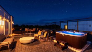 A rooftop terrace with a hot tub, seating area, and a view of the night sky. - Rooftop Hot Tub Skyline Views Near Broadway (Nashville)