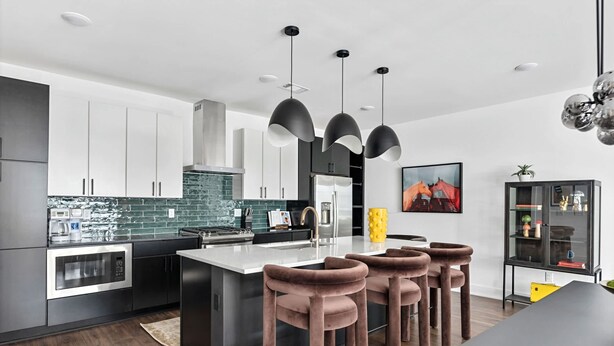 A modern kitchen with a central island, pendant lights, and bar stools. - Rooftop Hot Tub Skyline Views Near Broadway (Nashville)