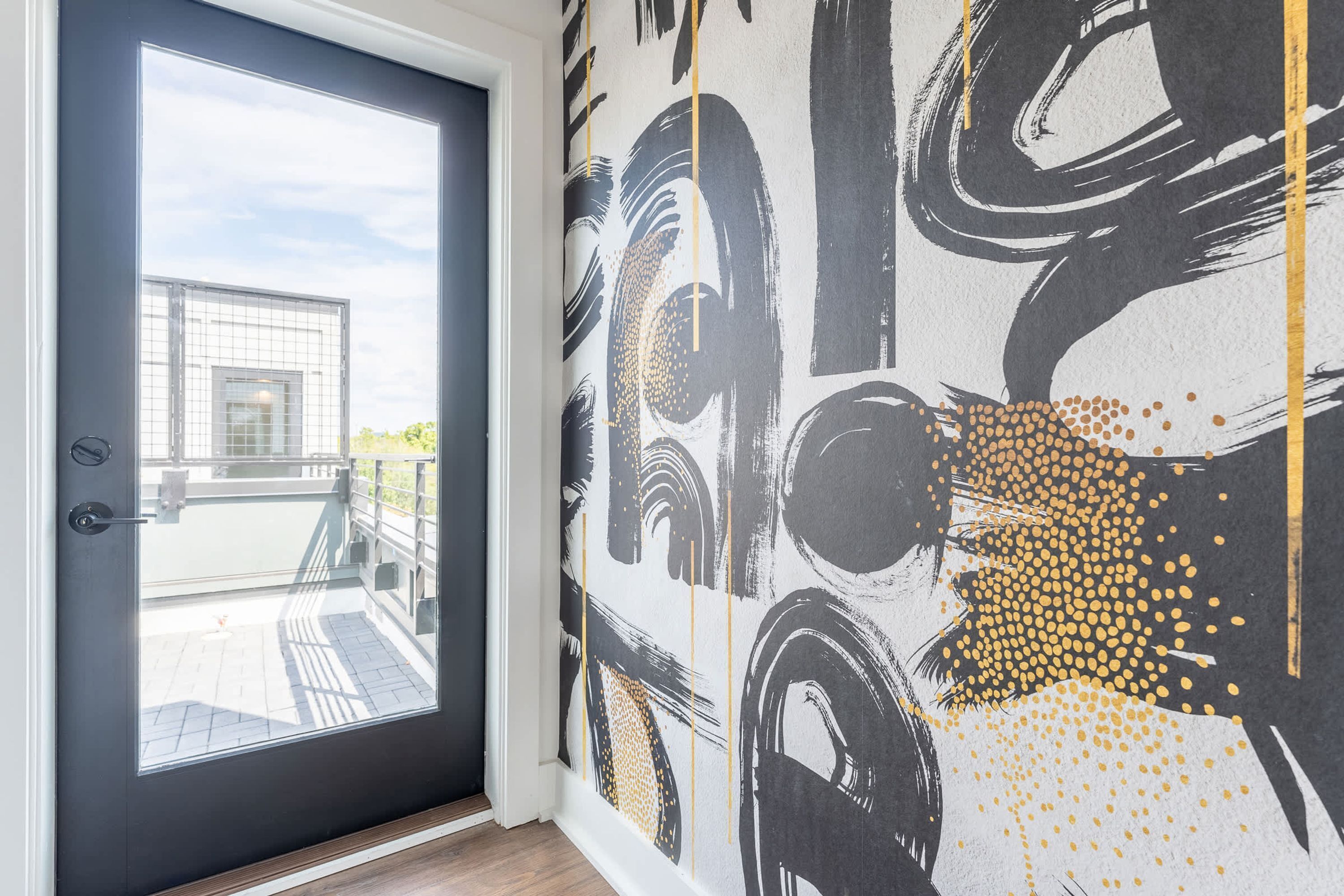 A room with a large window, a door, and a wall with abstract art.