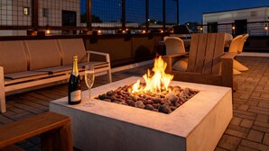 A rooftop terrace with a fire pit, seating, and a bottle of champagne. - Rooftop Fire Pit Skyline Views Near Broadway (Nashville)