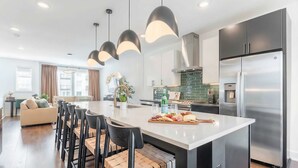 A modern kitchen with a central island, stainless steel appliances, and pendant lighting. - Rooftop Fire Pit Skyline Views Near Broadway (Nashville)