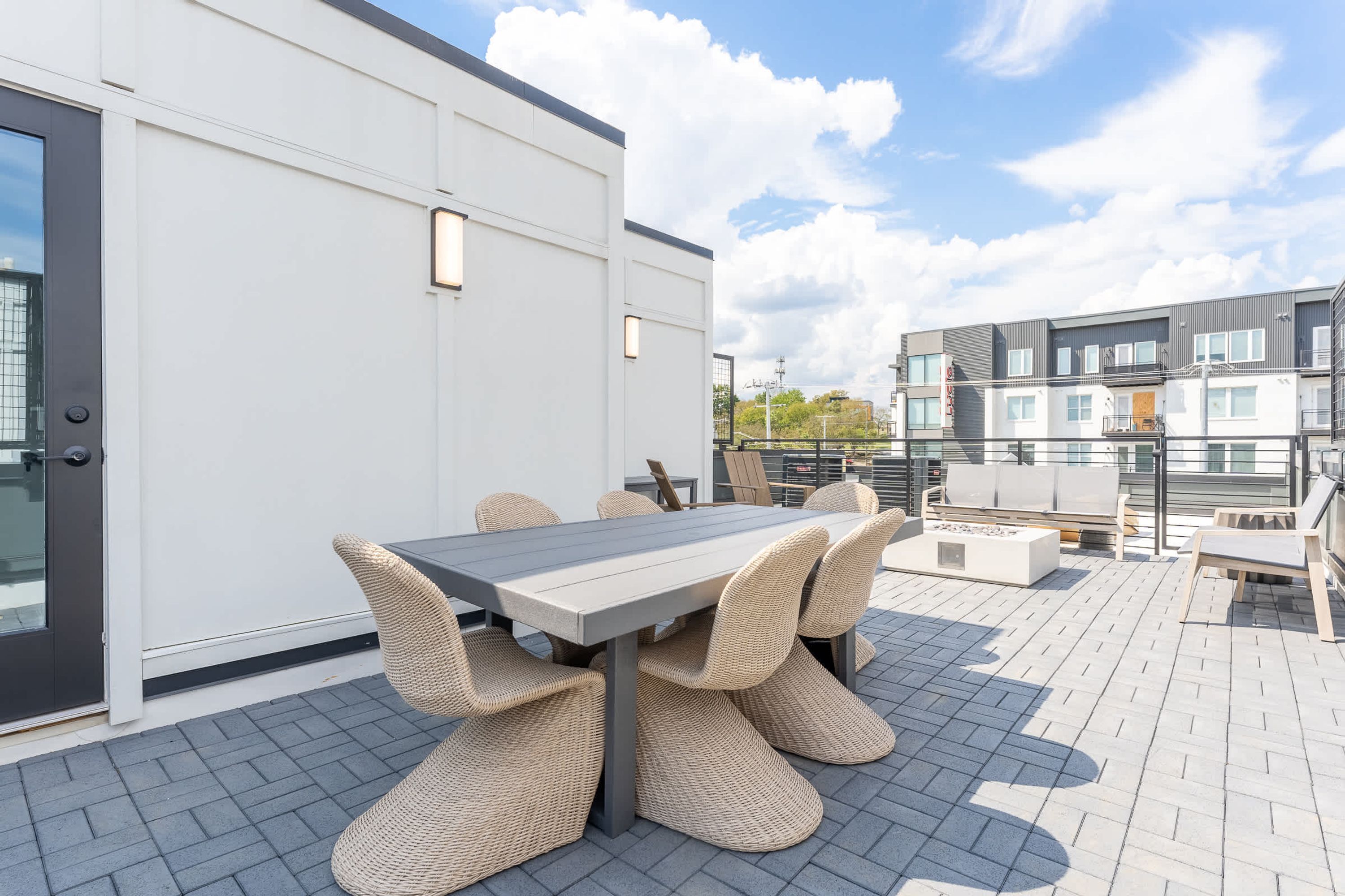 An outdoor patio with a dining table and chairs, a sofa, and a small fire pit.