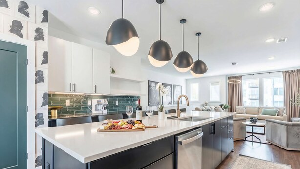 A modern kitchen with a central island, black cabinets, and pendant lighting. - Rooftop Fire Pit Skyline Views Near Broadway (Nashville)