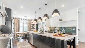 A modern kitchen with a central island, black cabinets, and pendant lighting. - Rooftop Fire Pit Skyline Views Near Broadway (Nashville)