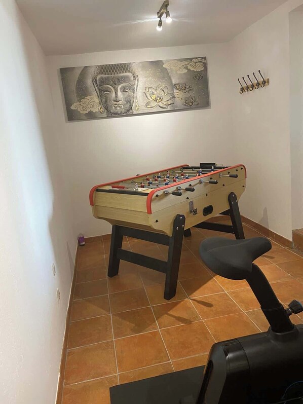 A room with a foosball table, a chair, and a wall-mounted artwork.
