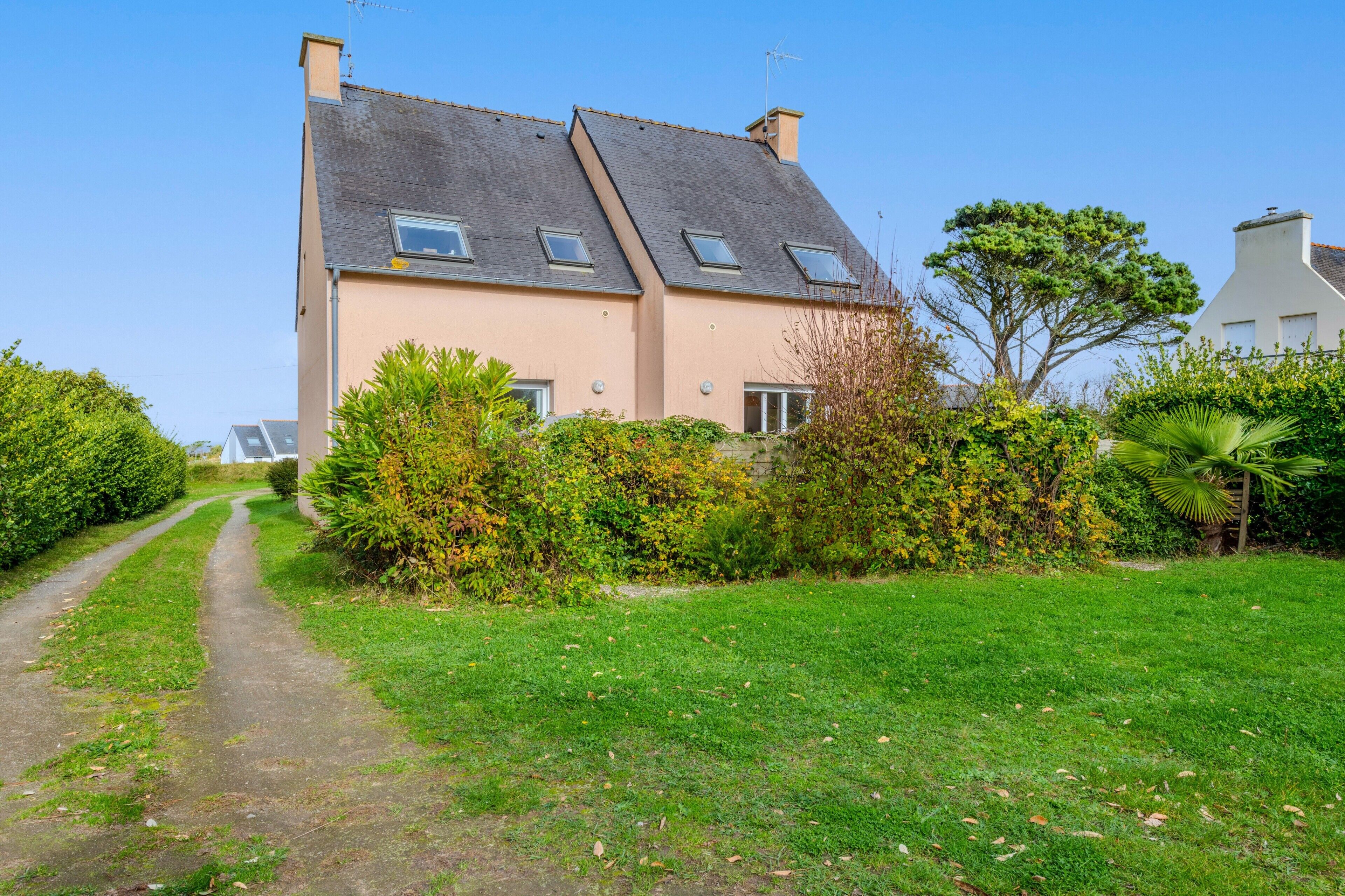 A two-story house with a sloped roof, a pathway leading to the entrance, and a well-maintained garden.