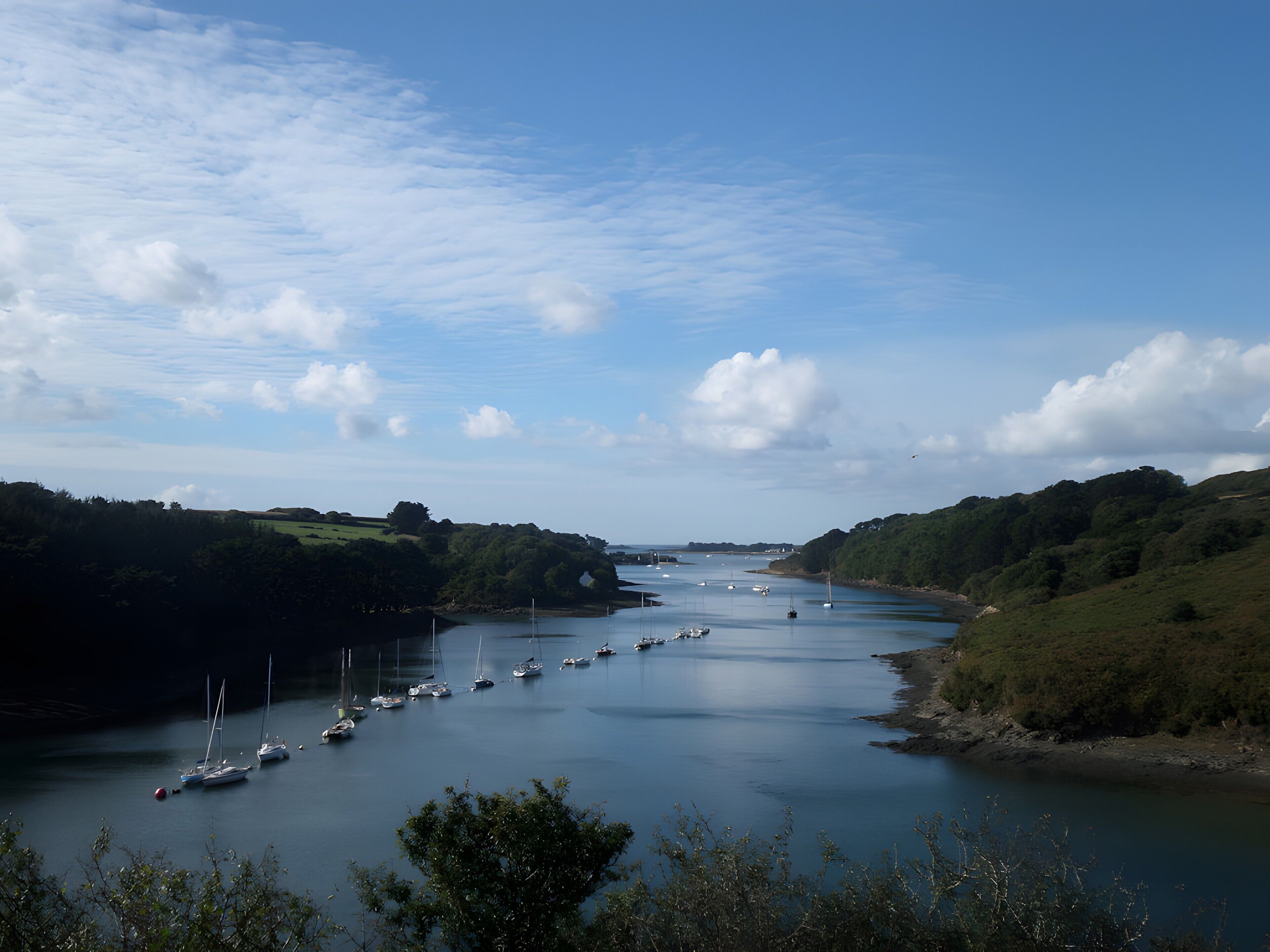 Une rivière où l’on peut naviguer, bordée de verdure et entourée de collines.