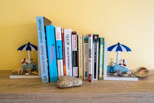 A collection of books with beach-themed illustrations and a small figurine of a girl with an umbrella.