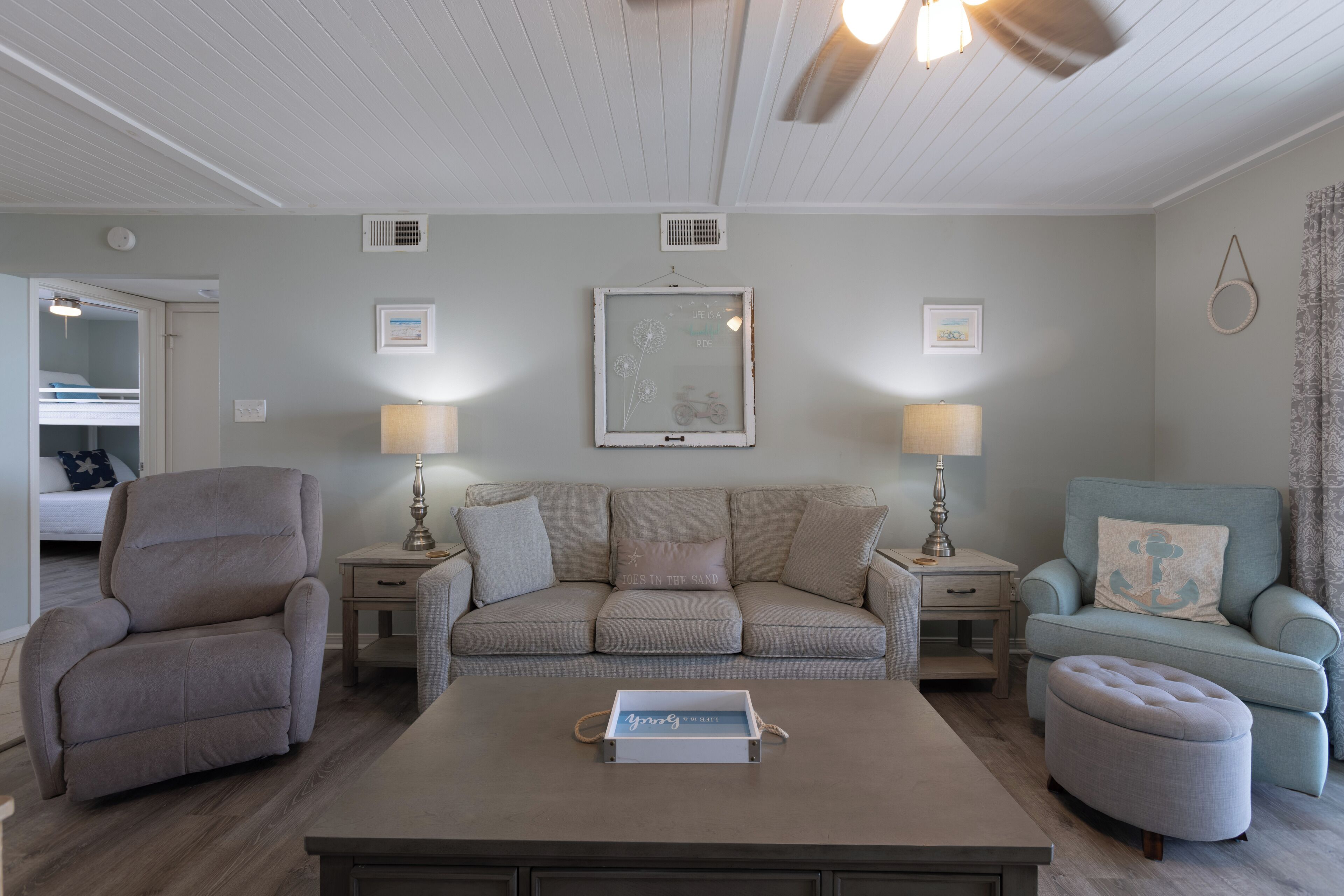 A living room with a sofa, armchairs, a coffee table, and a side table with lamps.