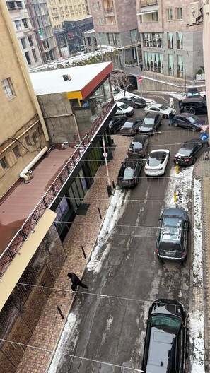 Ilmakuva parkkipaikasta, jossa on useita autoja, jalankulkijoiden käytävä ja taustalla näkyviä rakennuksia.