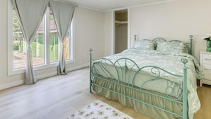 A bedroom with a metal bed frame, a white nightstand, and a window with curtains.