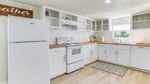 A modern kitchen with white cabinetry, a built-in oven, and a refrigerator.