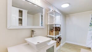 A bathroom with a white sink, mirror, and shelves with baskets.