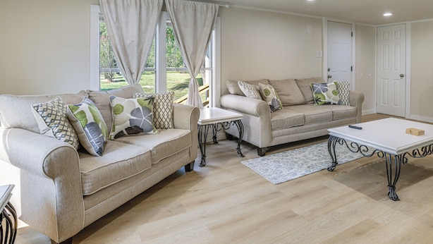 A living room with two beige sofas, a white coffee table, and a patterned rug.