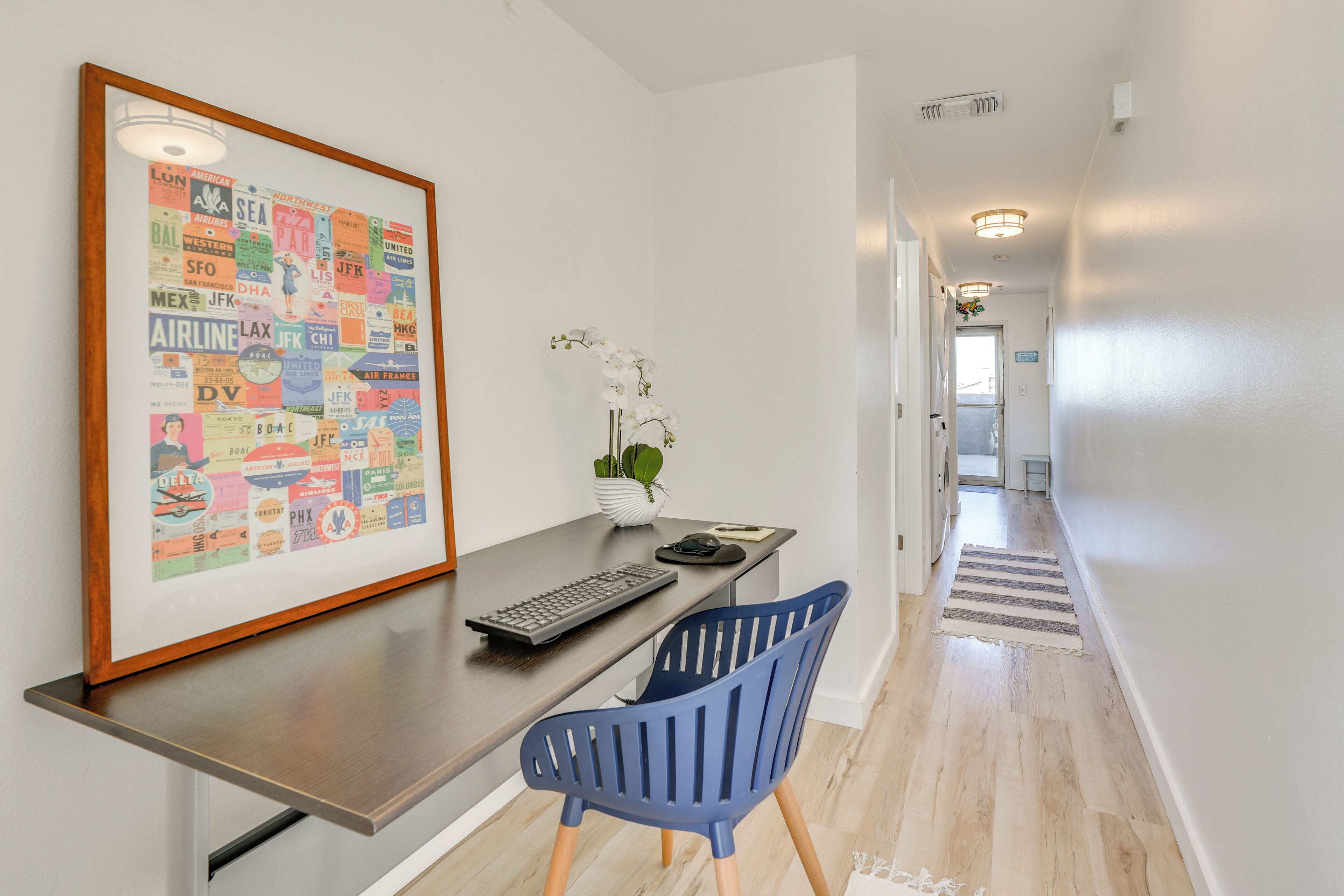 Une chambre d’hôtel moderne équipée d’un bureau, d’une chaise et d’un plan des itinéraires de l’aéroport, encadré et accroché au mur.
