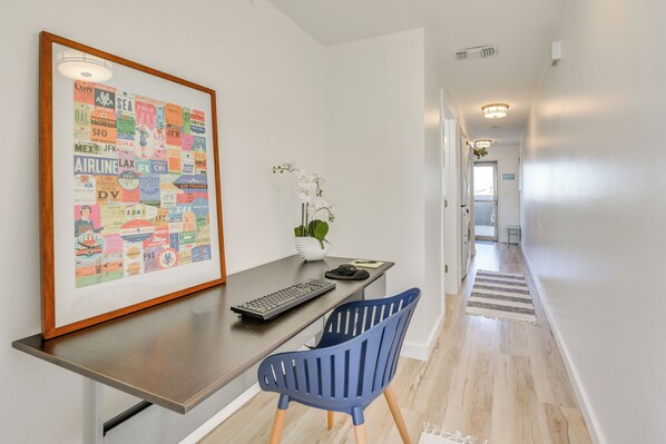 Une chambre d’hôtel moderne équipée d’un bureau, d’une chaise et d’un plan des itinéraires de l’aéroport, encadré et accroché au mur.