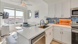 A modern kitchen with white cabinetry, a built-in oven, and a large island with a sink. - Walk to Sand! Modern Okaloosa Island Condo (Fort Walton Beach)