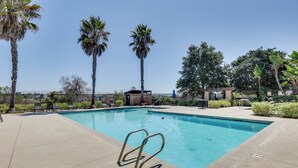 A swimming pool with a metal ladder, surrounded by palm trees and a fence. - Walk to Public Transit: Gated Oceanside Abode! (Oceanside)