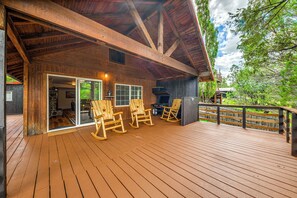 Une terrasse en bois avec des fauteuils à bascule et un espace barbecue.