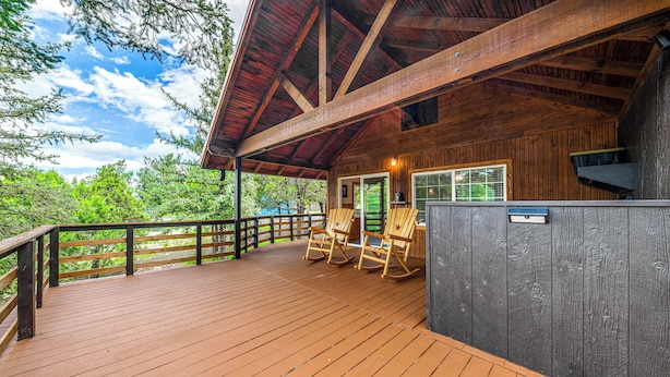 Un patio in legno con poltrone a dondolo e una zona riparata con finestra.