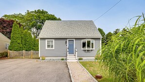 A single-story house with a gray exterior, a front door, and a small porch. - Coastal Charmer < 1 Mi to South Kingstown Beach (South Kingstown)