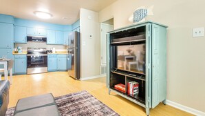 Eine moderne Küche mit blauen Schränken, Edelstahlgeräten und einem türkisfarbenen Schrank mit Fischdekor.