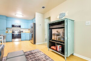 Una cocina moderna con armarios azules, electrodomésticos de acero inoxidable y un mueble azul verdoso decorado con un pez.