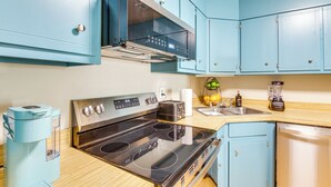 Eine Küche mit blauen Schränken, einem Edelstahlherd, einer Kaffeemaschine und einem Mixer.