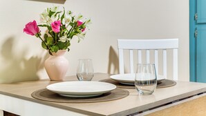Ein Esstisch mit Blumen in einer Vase, zwei Tellern und zwei Gläsern.