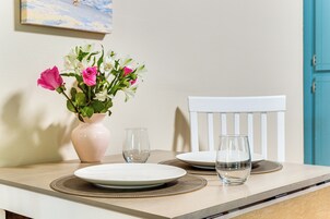 Una mesa de comedor con un jarrón de flores, dos platos y dos vasos.