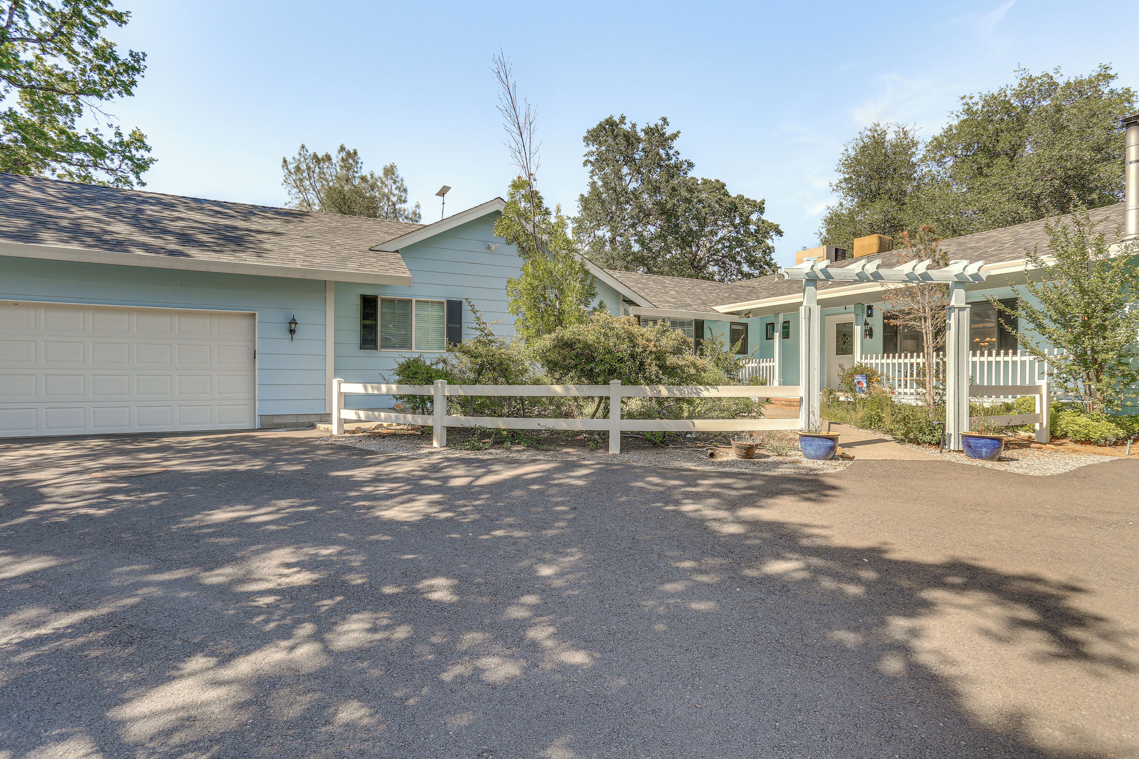 A light blue single-story house with a white garage, a covered porch, and a fenced yard.