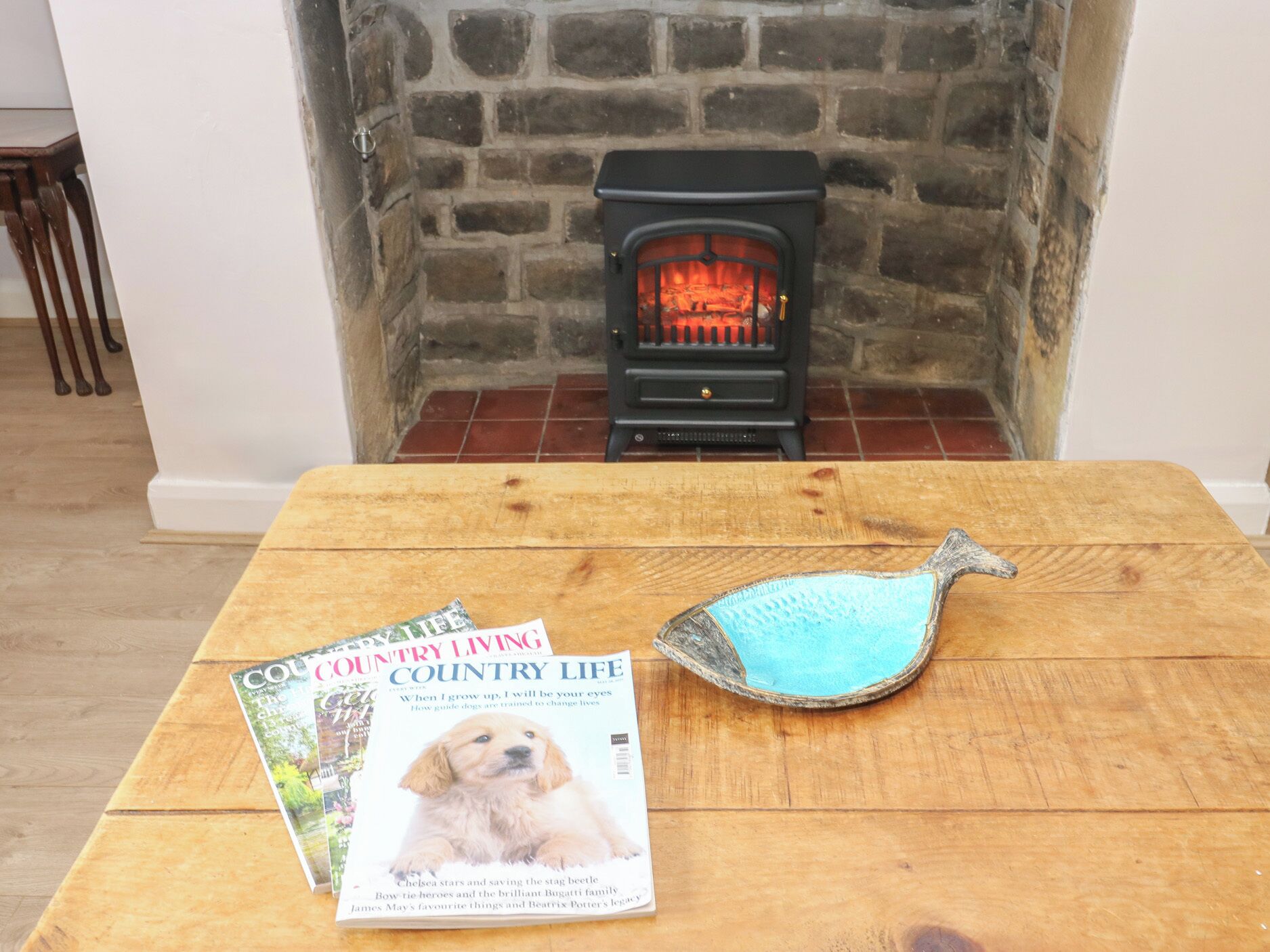 A magazine on a wooden table with a fireplace in the background.