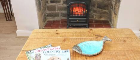 Una revista sobre una mesa de madera, con una chimenea al fondo.