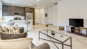 A modern living room with a glass coffee table, a sofa, and a television. - Lake + Mtn Views: Couple's Apt in Apache Junction (Apache Junction)