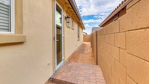A narrow outdoor corridor with a brick pathway, beige walls, and a tiled roof. - Lake + Mtn Views: Couple's Apt in Apache Junction (Apache Junction)