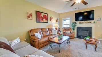 A living room with a brown leather sofa, a coffee table, a fireplace, and a television mounted on the wall.