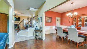 A spacious living area with hardwood flooring, a dining table with chairs, a staircase, and a kitchen area in the background. - Fenced Yard & Patio! Family Home Near Fort Benning (Columbus)