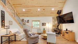 A spacious living area with a wooden staircase, a sofa, a recliner, a TV mounted on the wall, and a stone fireplace. - Paddle, Play & Relax: Home w/ Pioneer Lake Access! (Conover)
